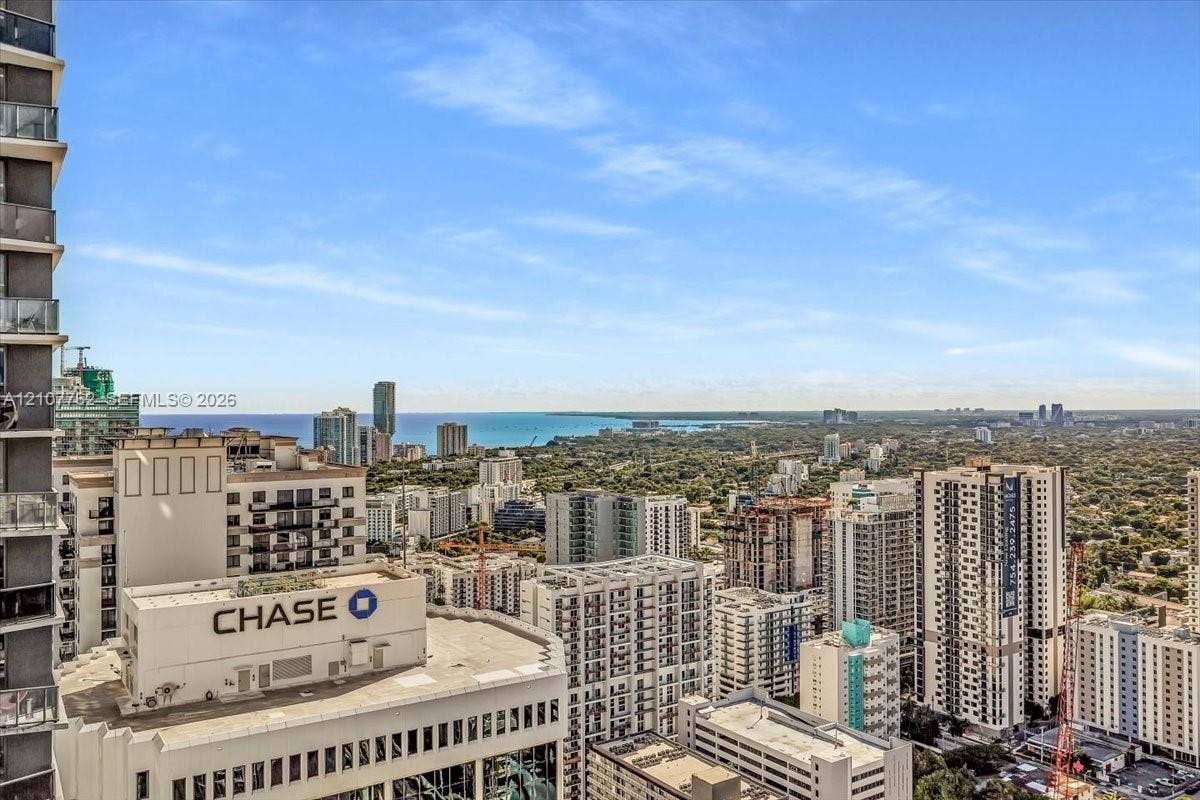 High-rise residential balcony featuring glass panel railings and expansive urban and coastal horizon scenery