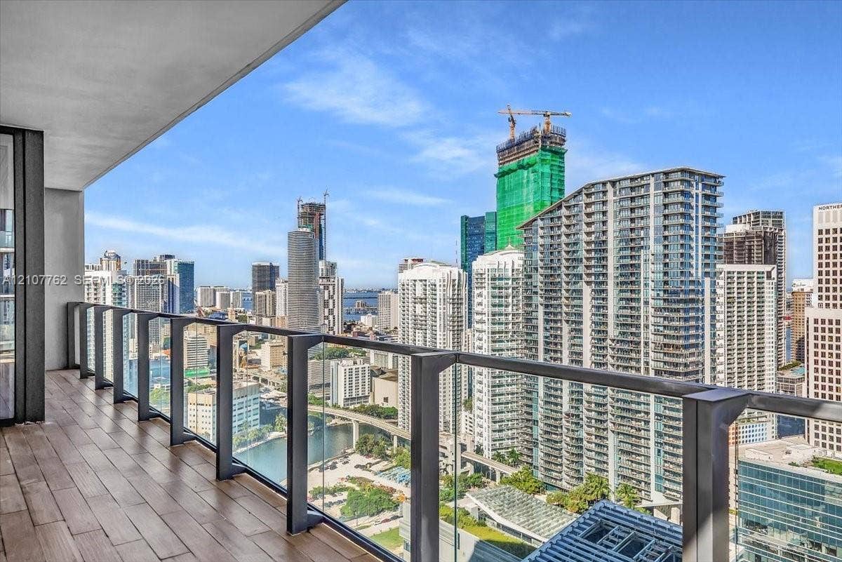 Covered balcony featuring wood-finish flooring and glass panel railing
