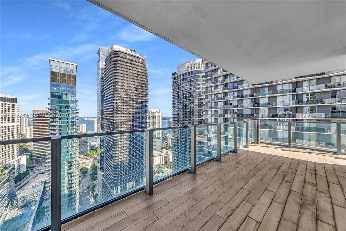 Covered balcony featuring wood-finish flooring and a glass railing
