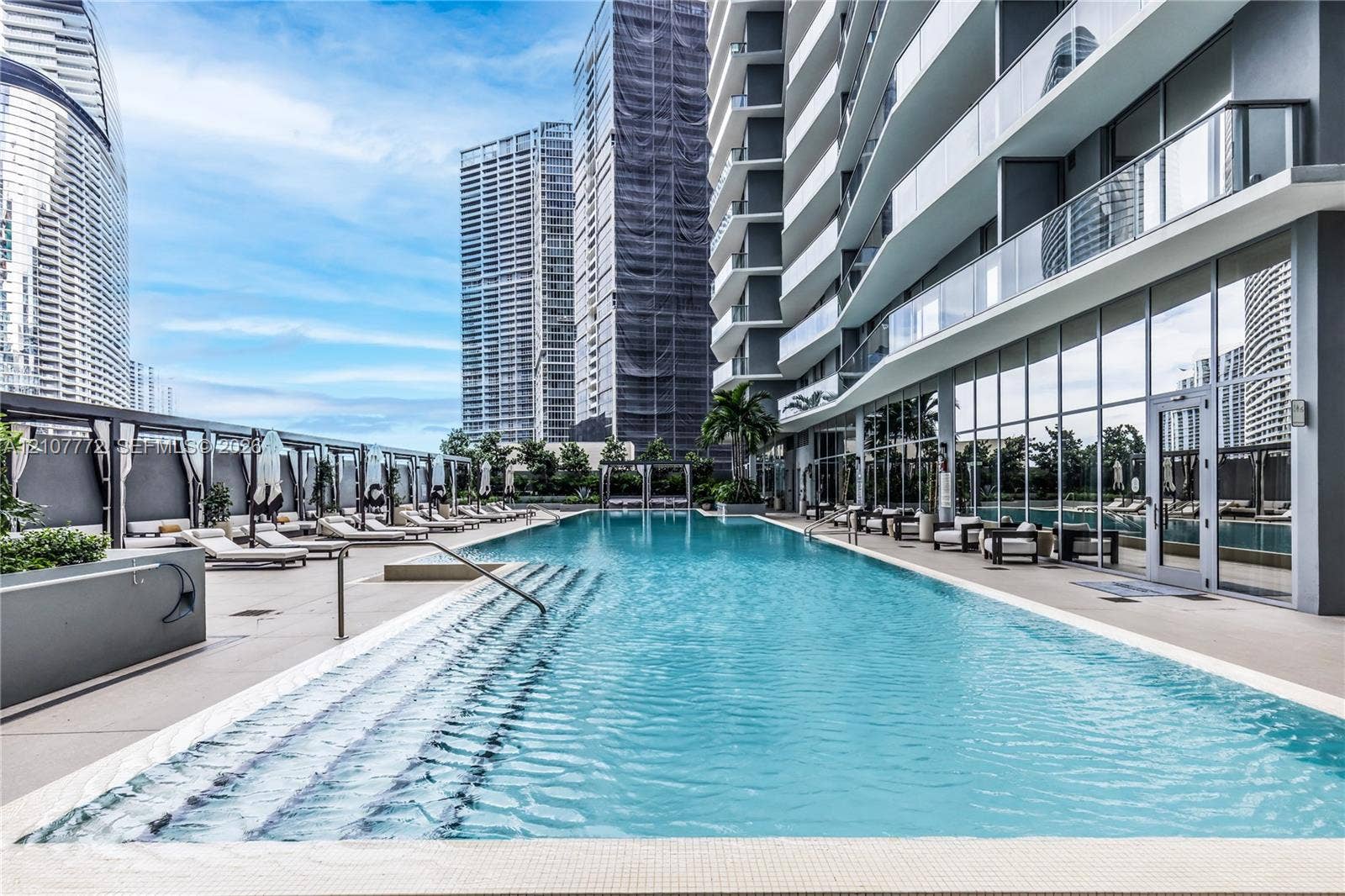 77 SE 5th Street, #1210, Miami, Miami, FL 33131 Outdoor lap pool featuring tiled steps, stone-finish decking, glass panel railings, and metal pergolas