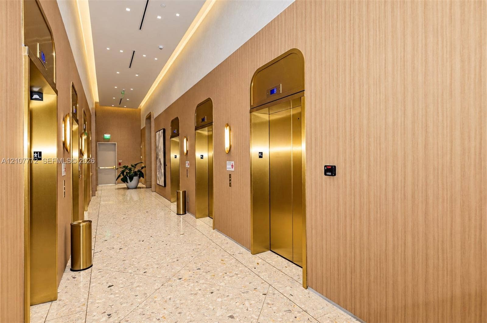 77 SE 5th Street, #1210, Miami, Miami, FL 33131 Elevator lobby featuring metallic gold-finish doors, wood-paneled walls, recessed ceiling lighting, and polished stone tile flooring