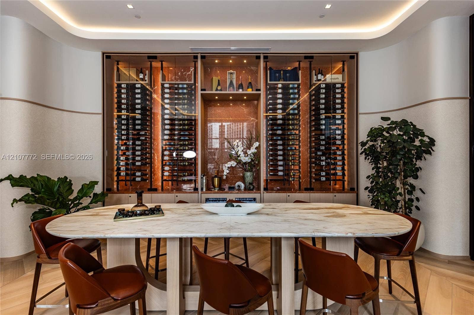 77 SE 5th Street, #1210, Miami, Miami, FL 33131 Custom built-in glass-front wine display with integrated accent lighting and natural stone-finish back panel, featuring curved wall detailing and chevron-pattern wood-finish flooring