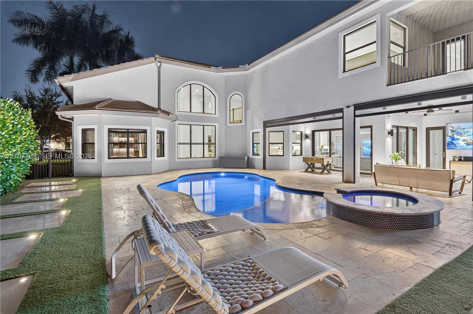 9328 Tropez Lane, Delray Beach, FL 33446 Stucco exterior featuring a resort-style pool, raised spa with tile surround, natural stone paver patio, and covered outdoor living area