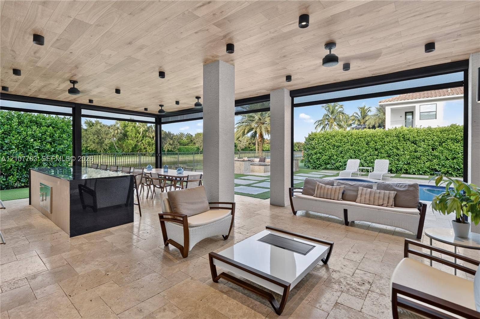 9328 Tropez Lane, Delray Beach, FL 33446 Covered outdoor living space featuring natural stone flooring, wood-plank ceiling, recessed lighting, and a built-in outdoor kitchen with a dark-toned island