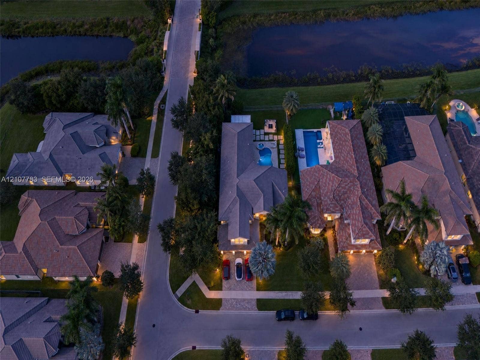9328 Tropez Lane, Delray Beach, FL 33446 Aerial perspective of residential properties featuring tile roofing, paved driveways, private swimming pools, and landscaped perimeters situated along a waterfront boundary