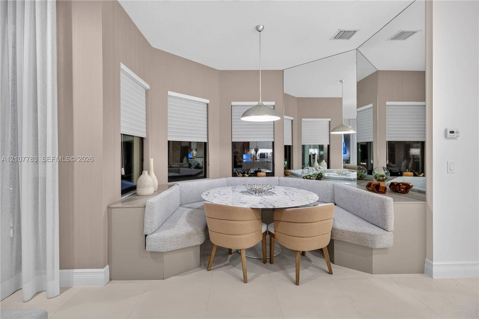 9328 Tropez Lane, Delray Beach, FL 33446 Custom built-in upholstered banquette seating, floor-to-ceiling wall mirror, bay window configuration with integrated blinds, and polished pendant lighting