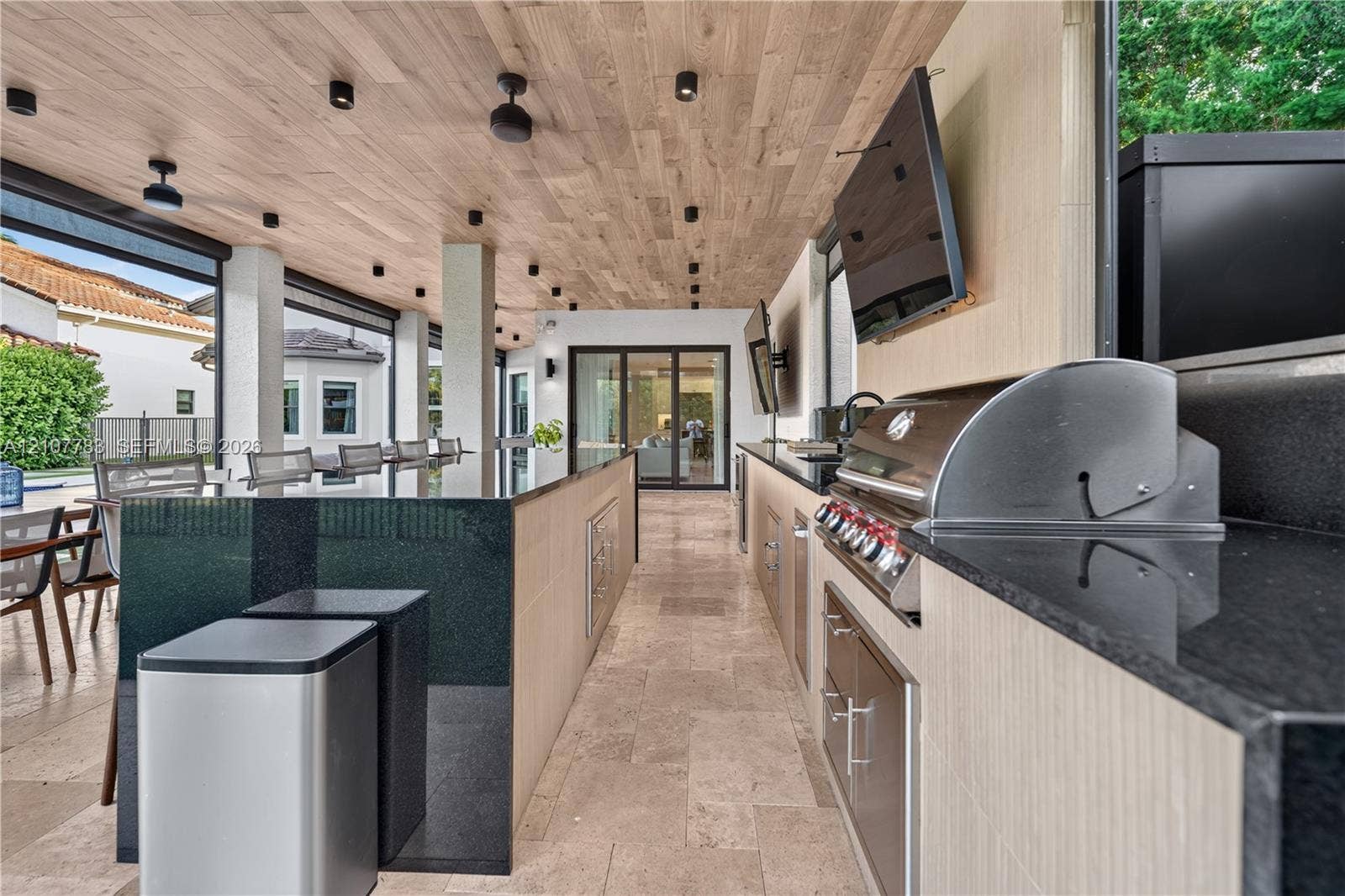 9328 Tropez Lane, Delray Beach, FL 33446 Outdoor kitchen featuring a stone-tile floor, wood-finish ceiling, dark stone countertops, integrated stainless steel grill, and recessed lighting
