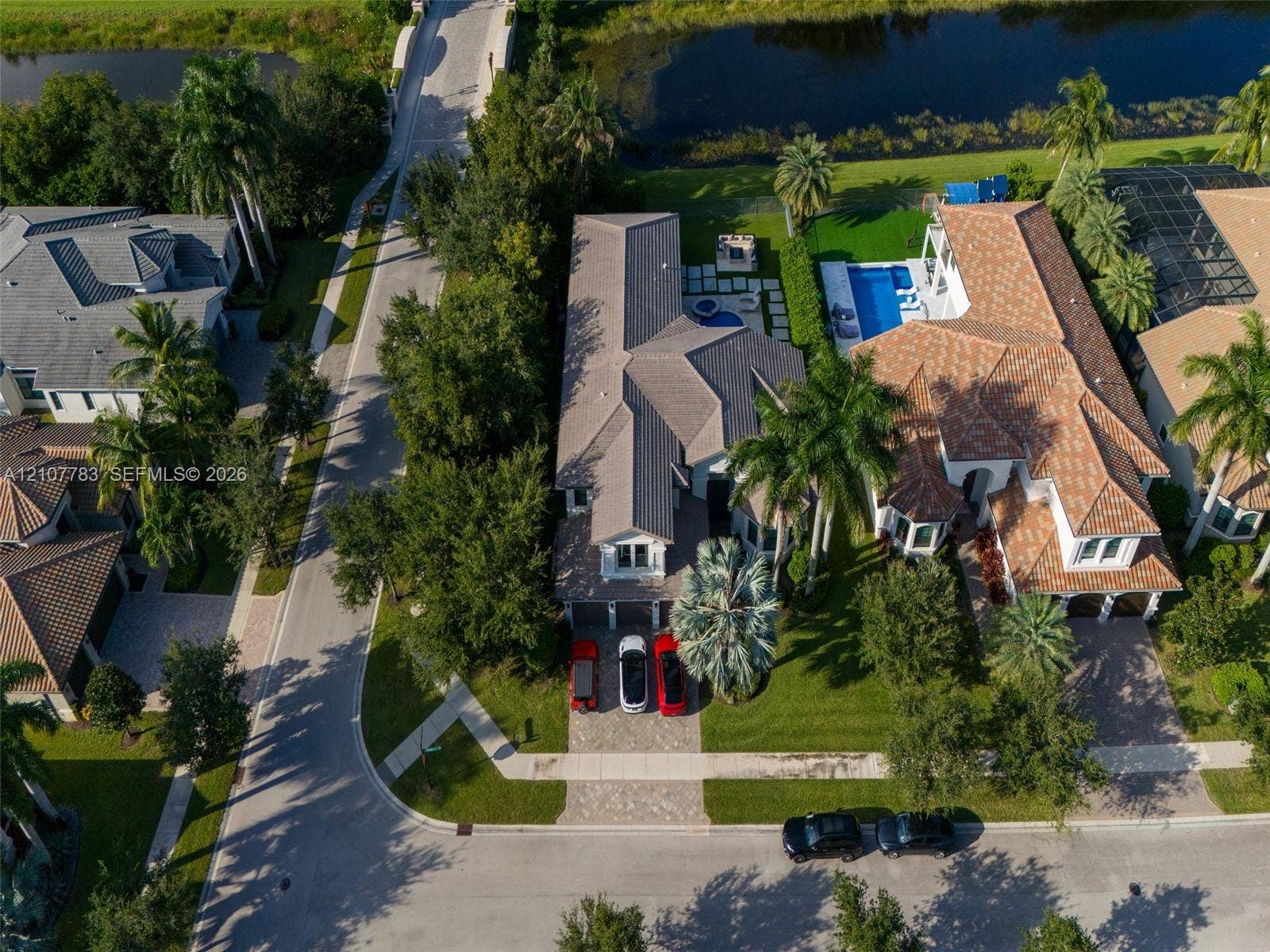 9328 Tropez Lane, Delray Beach, FL 33446 Aerial view featuring a multi-gabled roofline, paver driveway, mature landscaping, in-ground pool, and hardscaped patio area