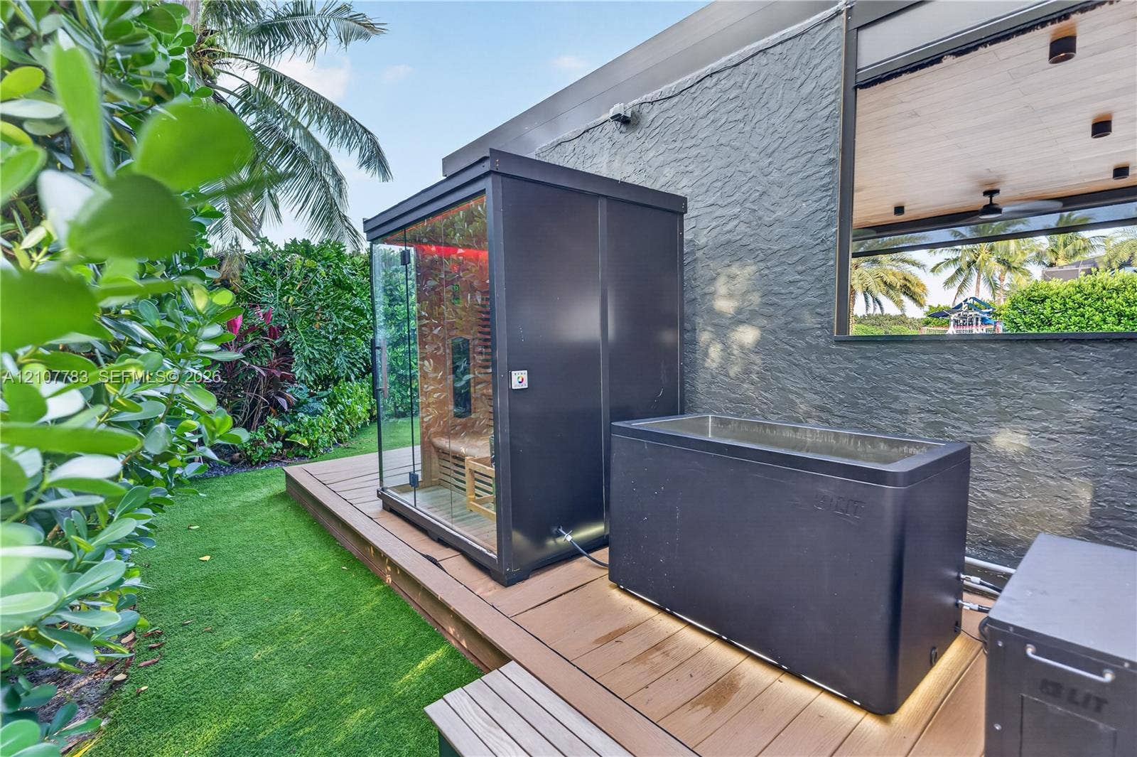 9328 Tropez Lane, Delray Beach, FL 33446 Outdoor space featuring a composite deck, glass-enclosed sauna, and a built-in plunge tub with under-mount lighting