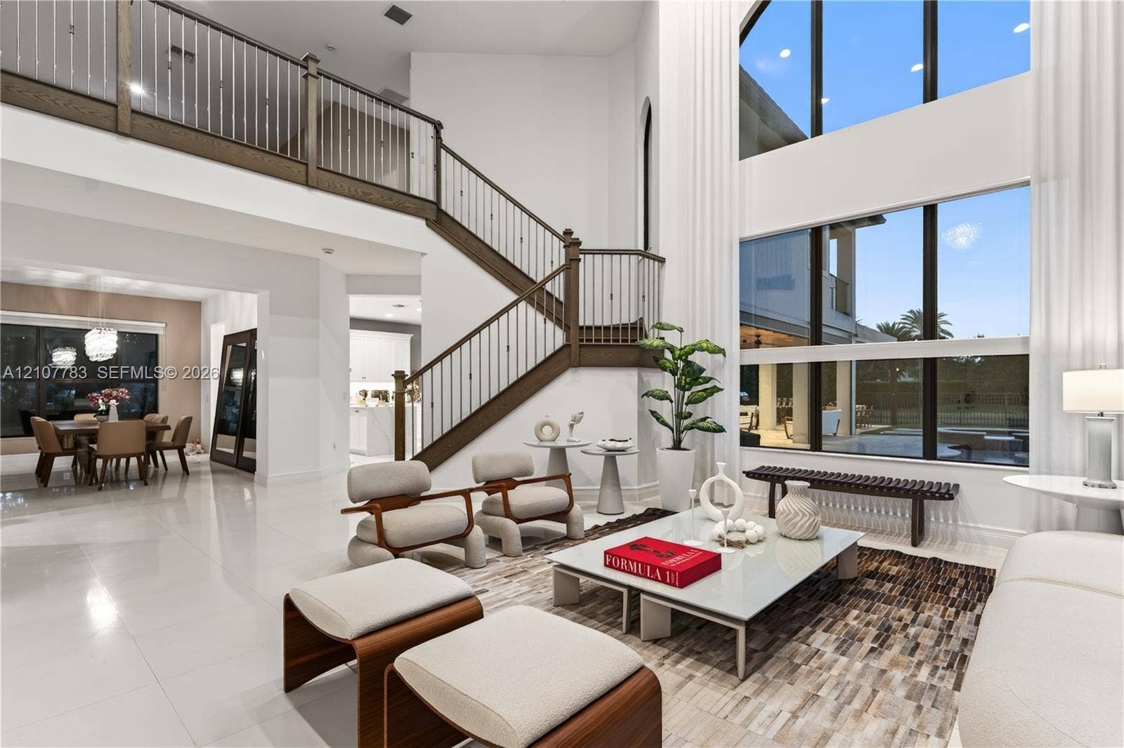 9328 Tropez Lane, Delray Beach, FL 33446 Two-story living area featuring floor-to-ceiling windows, porcelain tile flooring, and a grand staircase with wood-finished handrails and metal balusters