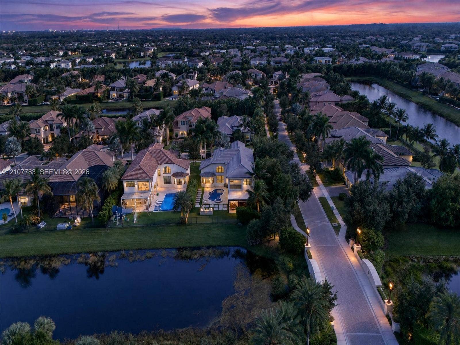 9328 Tropez Lane, Delray Beach, FL 33446 Aerial perspective of a residential neighborhood featuring waterfront lots, paved roadways, mature palm trees, and rear-yard swimming pools