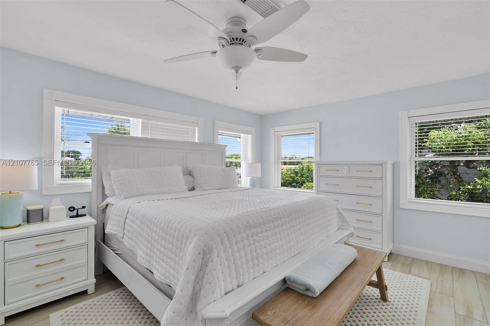 Bright interior space featuring multi-pane windows, neutral wall tones, wood-finish flooring, and a central ceiling fan