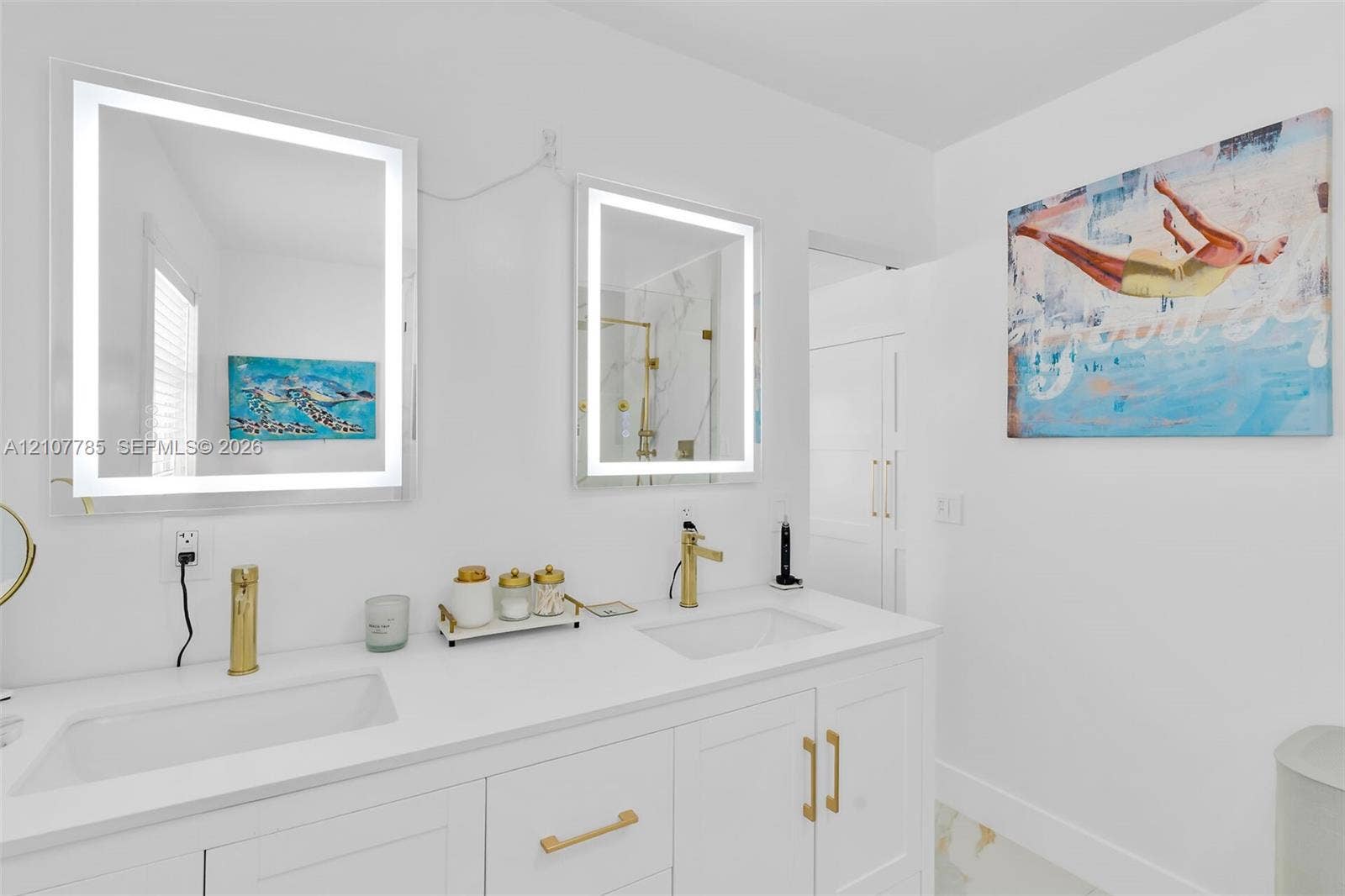Dual-sink vanity featuring integrated rectangular basins, white stone-finish countertop, and gold-toned hardware, complemented by two rectangular LED-lit mirrors and matching gold-toned faucets