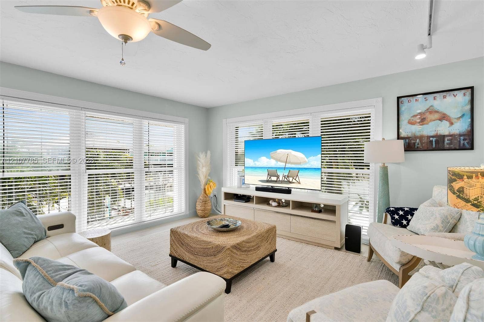 Living area featuring multi-panel windows with adjustable horizontal blinds, ceiling-mounted fan with integrated lighting, and track lighting fixtures