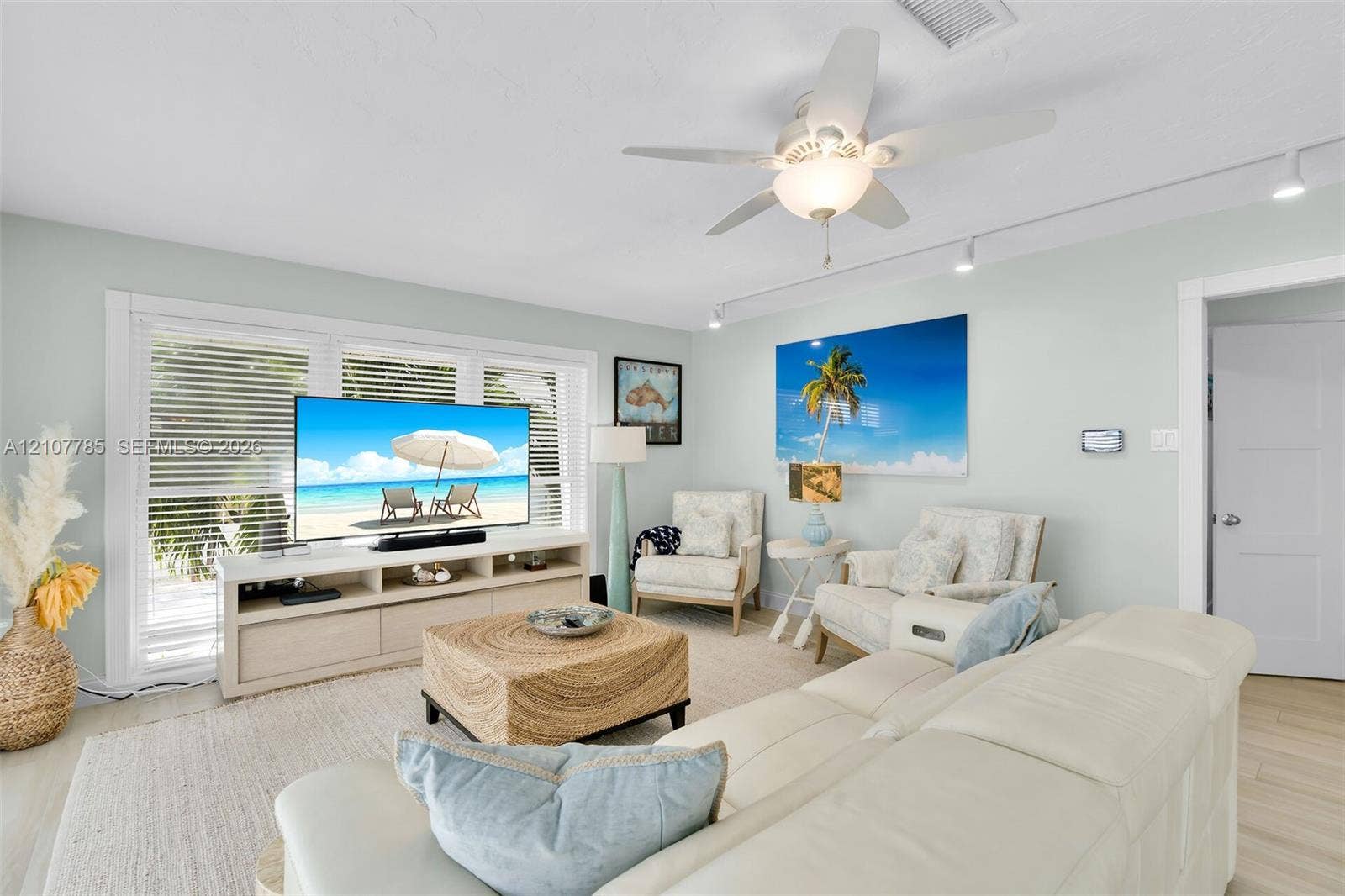 Living area featuring light-toned wood-finish flooring, recessed track lighting, a ceiling fan with integrated light fixture, and windows equipped with horizontal blinds