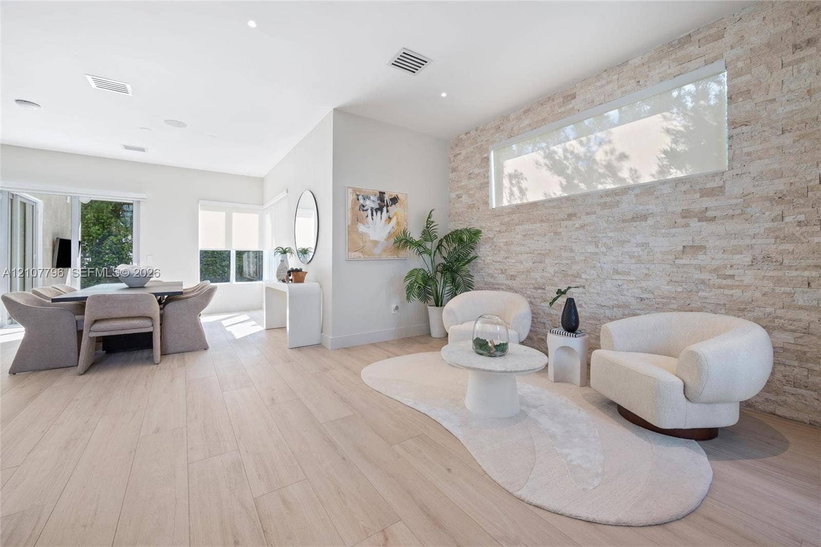 Textured stacked-stone accent wall, wide-plank light wood-finish flooring, recessed lighting, and horizontal clerestory window