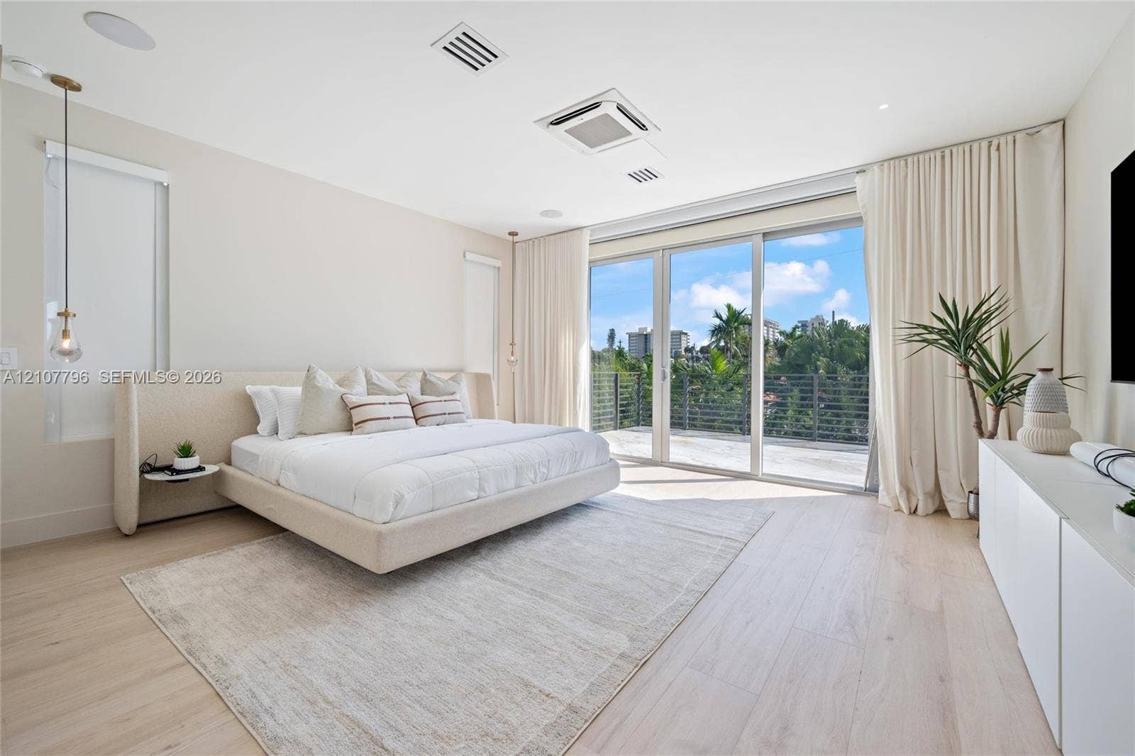 Expansive room featuring wood-finish flooring, recessed ceiling lighting, a built-in sound system, and floor-to-ceiling glass sliding doors opening to an outdoor balcony