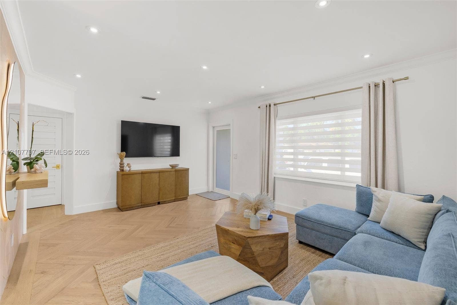 Herringbone-pattern wood-finish flooring, recessed lighting, crown molding, and a multi-lite exterior door with frosted glass paneling