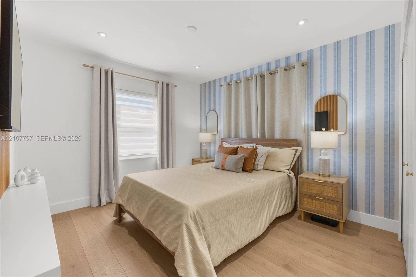 Bedroom featuring wood-finish flooring, recessed lighting, and a blue-and-white striped accent wall with dual wall-mounted mirrors