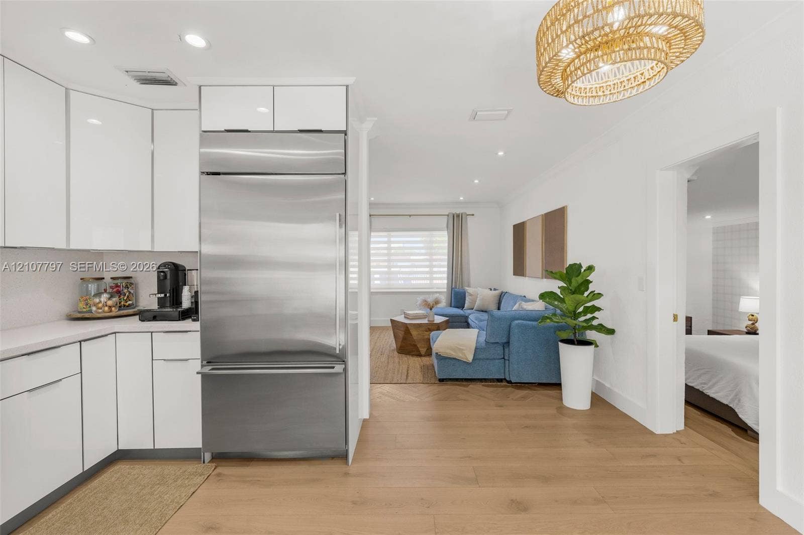 Kitchen featuring high-gloss white cabinetry, integrated stainless steel refrigerator, solid-surface countertops, recessed lighting, and wood-finish flooring