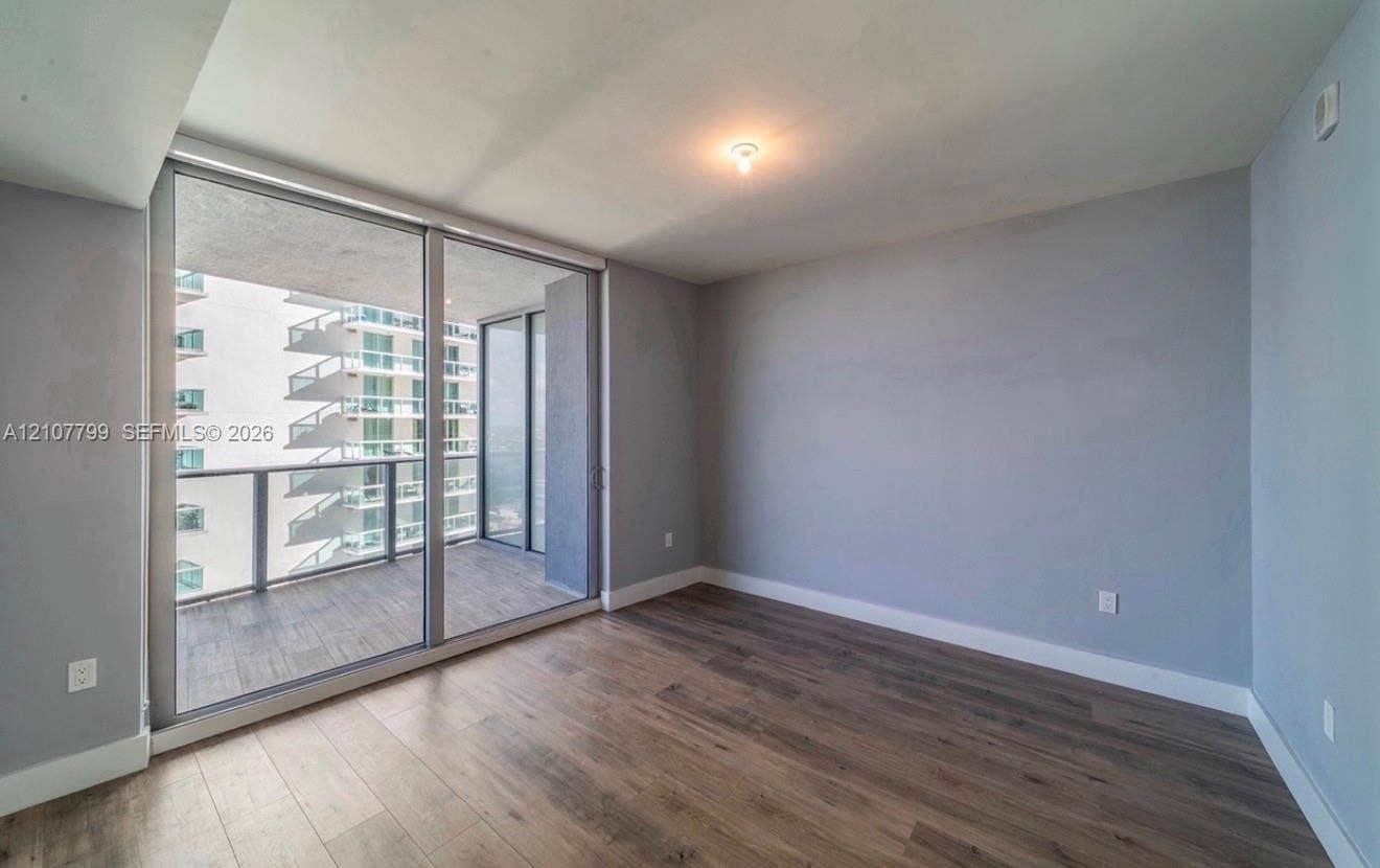 Wood-finish flooring, floor-to-ceiling glass sliding doors, and a private balcony with a metal railing