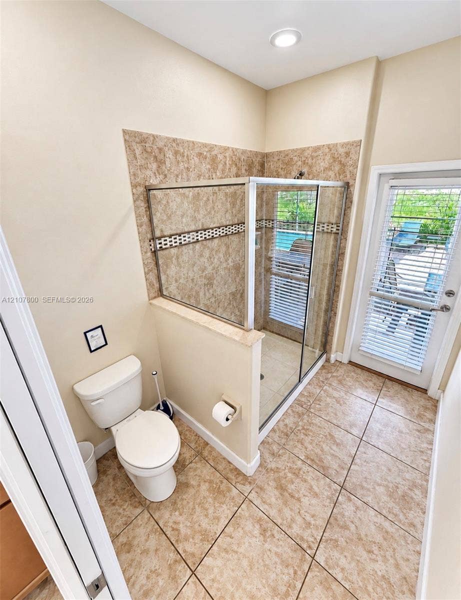1476 Moon Valley, Davenport, FL 33896 Enclosed glass-door shower featuring tile surround with decorative mosaic accent, ceramic tile flooring, recessed lighting, and a glass-paneled exterior door