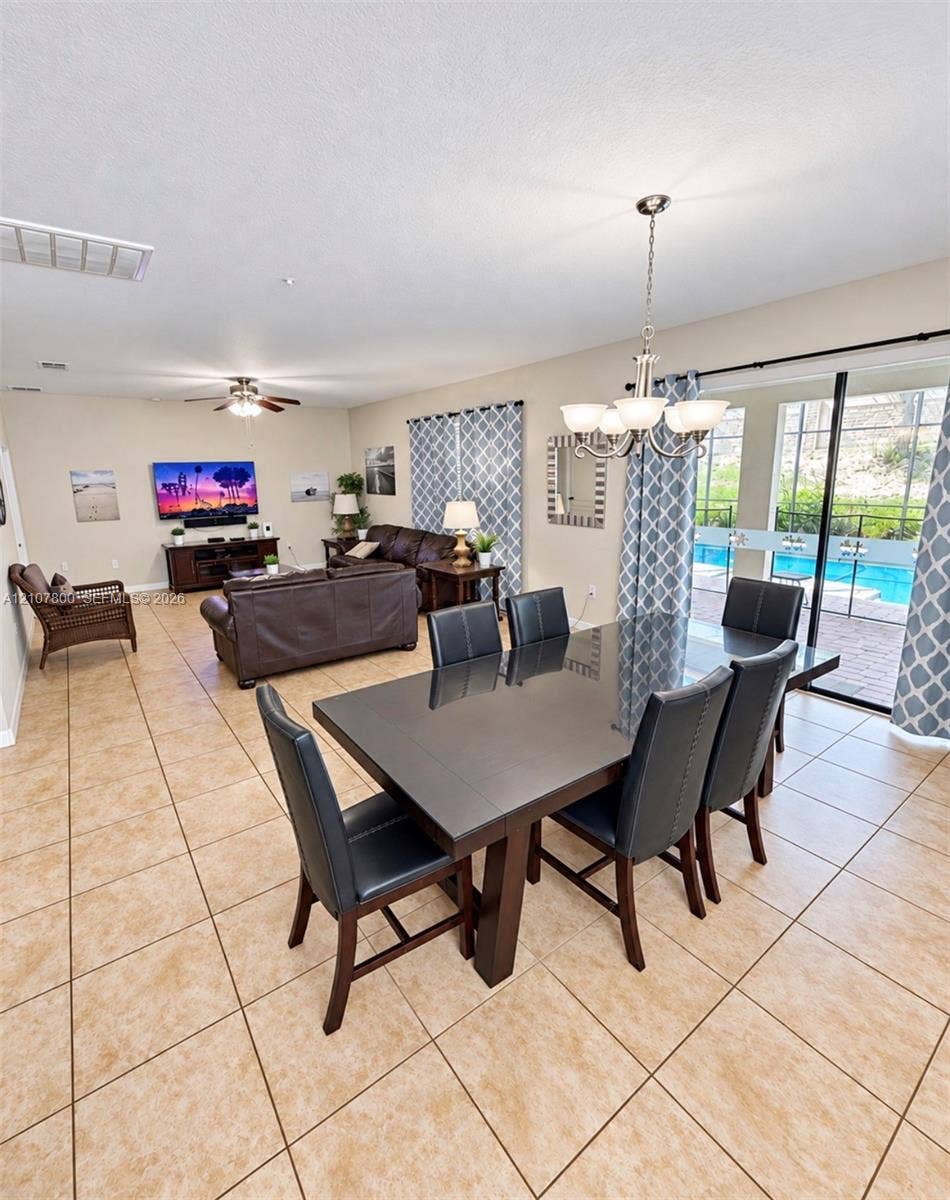 1476 Moon Valley, Davenport, FL 33896 Open-concept interior featuring oversized tile flooring, a multi-arm chandelier, and sliding glass doors with direct exterior access to a pool