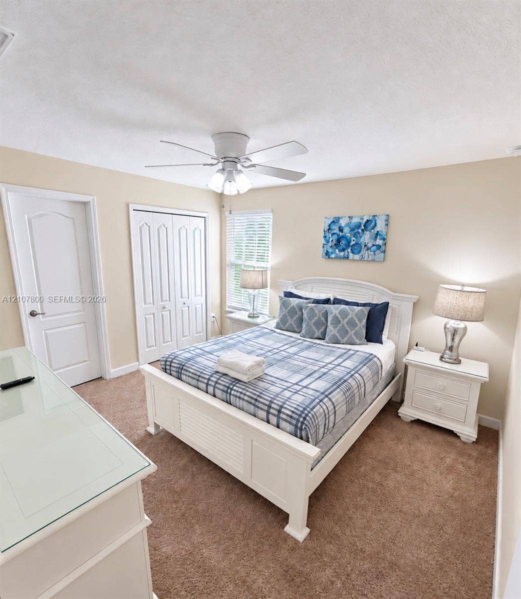 1476 Moon Valley, Davenport, FL 33896 Bedroom featuring neutral carpeting, a ceiling-mounted light fixture with a central fan, and a built-in closet with double doors