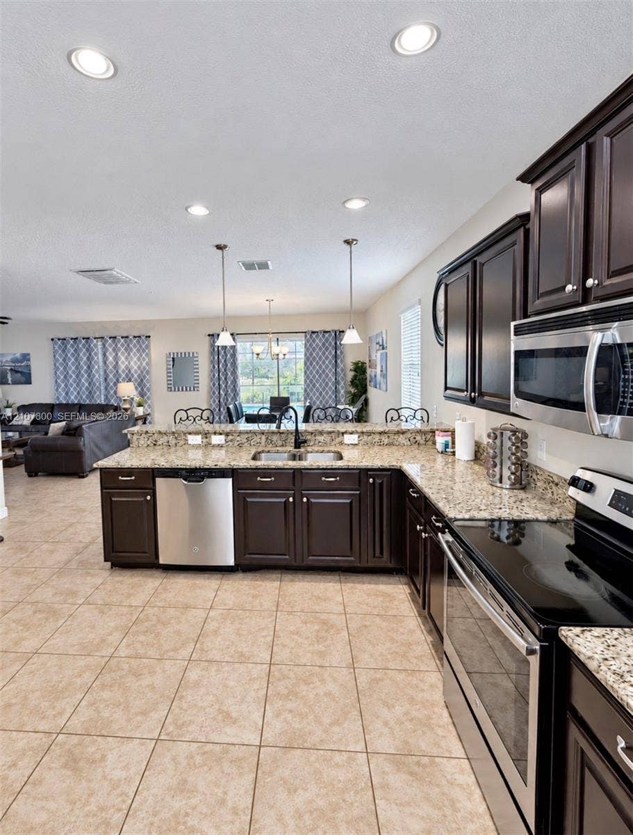 1476 Moon Valley, Davenport, FL 33896 Kitchen featuring dark cabinetry, stone-finish countertops, stainless steel appliances, tile flooring, and recessed lighting