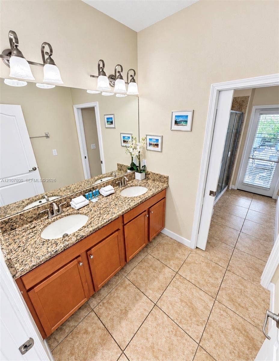 1476 Moon Valley, Davenport, FL 33896 Dual-sink vanity with natural stone countertops, tile flooring, and integrated wall-mounted lighting