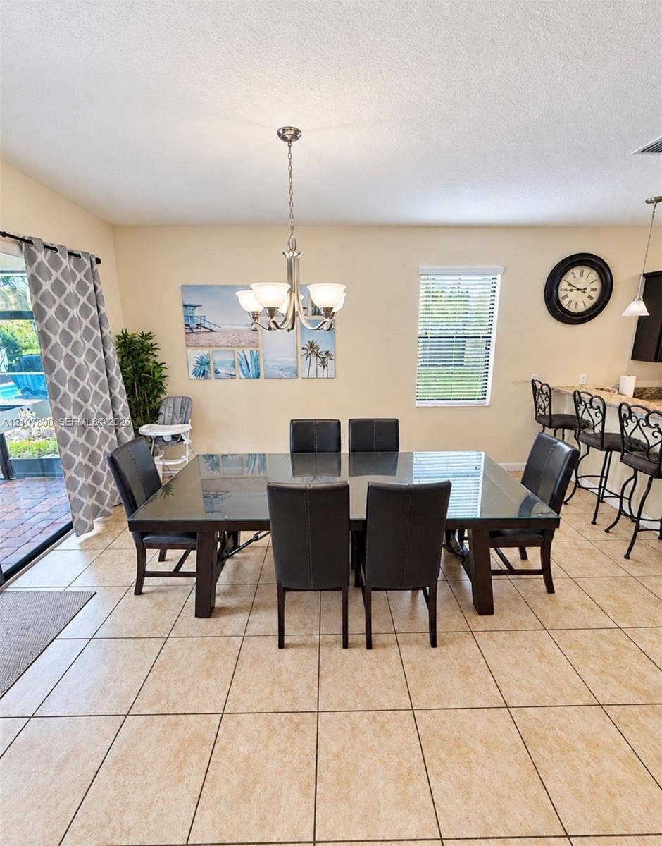 1476 Moon Valley, Davenport, FL 33896 Dining area featuring ceramic tile flooring, a multi-arm metal chandelier, and a breakfast bar with stone-finish countertop