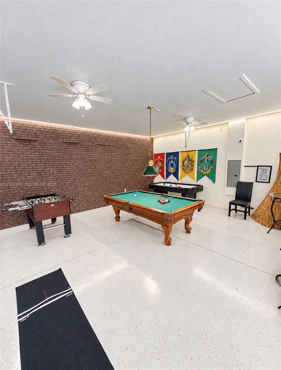 1476 Moon Valley, Davenport, FL 33896 Interior space featuring a brick accent wall, white speckled epoxy flooring, two ceiling fans, recessed perimeter lighting, and a pendant light fixture