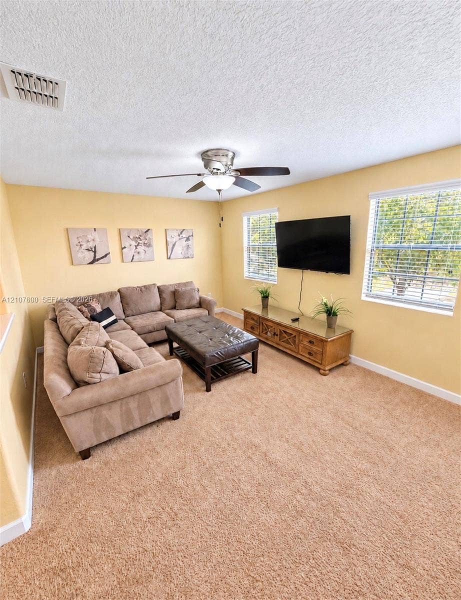 1476 Moon Valley, Davenport, FL 33896 Living area featuring wall-to-wall carpeting, dual windows, and a ceiling fan with light fixture