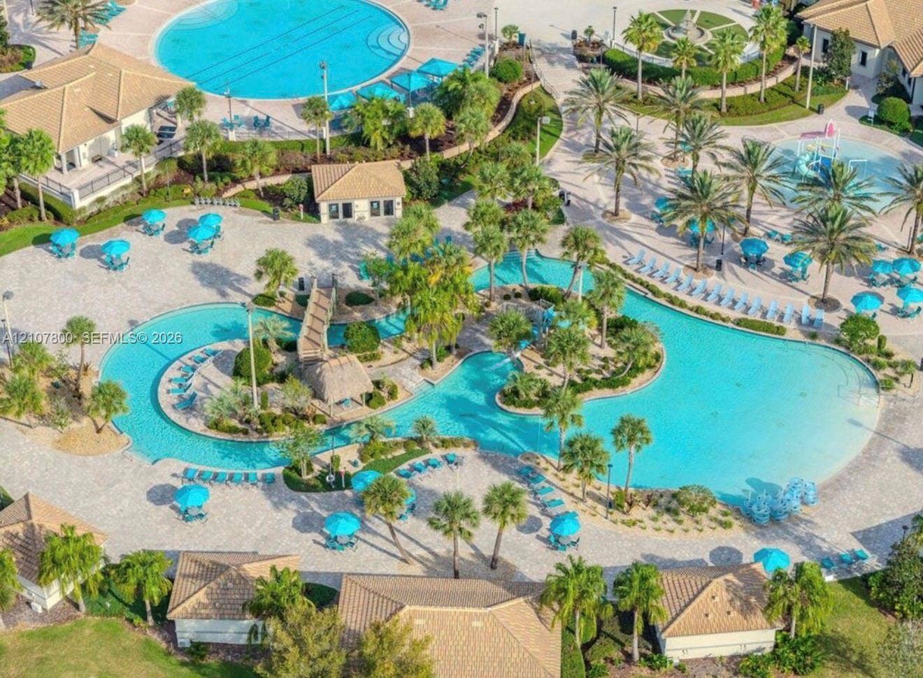 1476 Moon Valley, Davenport, FL 33896 Expansive resort-style aquatic complex featuring a winding lazy river, integrated swimming pools, a pedestrian bridge, and palm tree landscaping