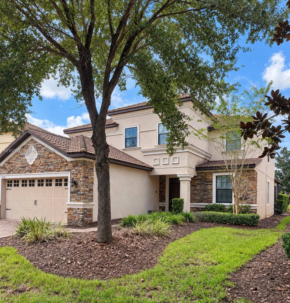 1476 Moon Valley, Davenport, FL 33896 Two-story stucco exterior featuring stone masonry accents, a tiled roof, multi-pane windows, and a multi-car garage