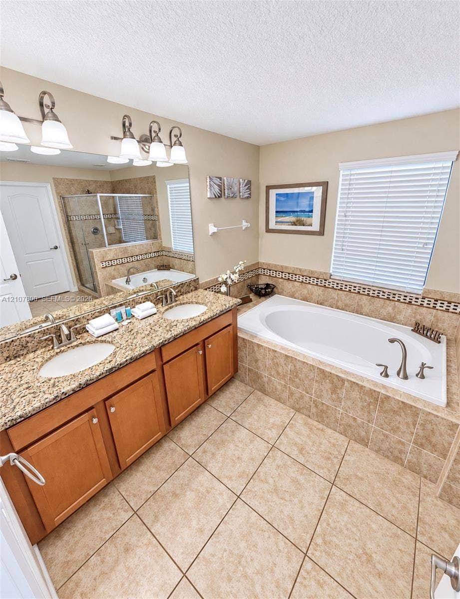 1476 Moon Valley, Davenport, FL 33896 Dual-sink vanity with stone-finish countertop, soaking tub with tile surround, walk-in glass shower, and ceramic tile flooring