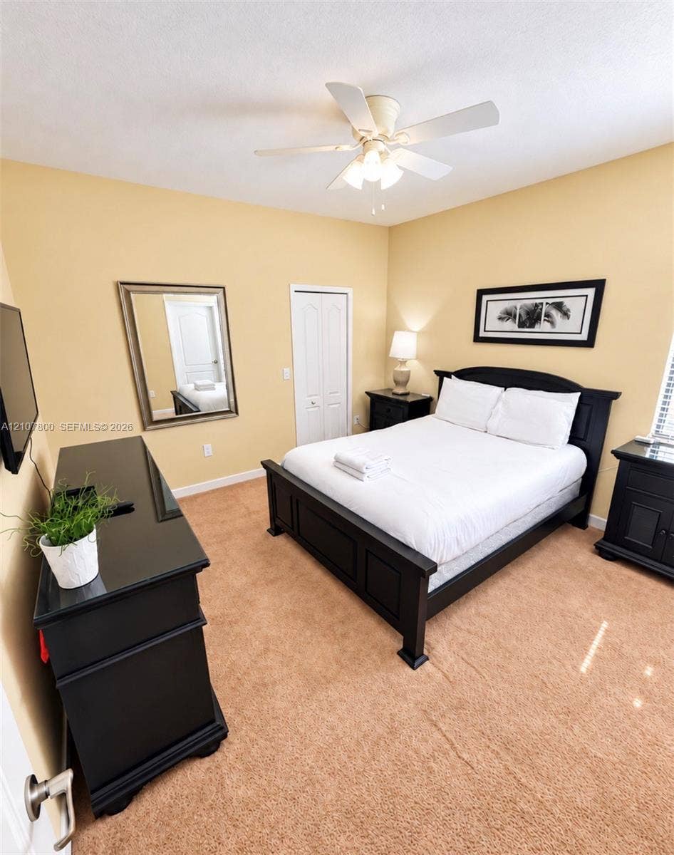 1476 Moon Valley, Davenport, FL 33896 Bedroom featuring neutral carpeting, a ceiling-mounted light fixture with a central fan, and a built-in closet with double doors