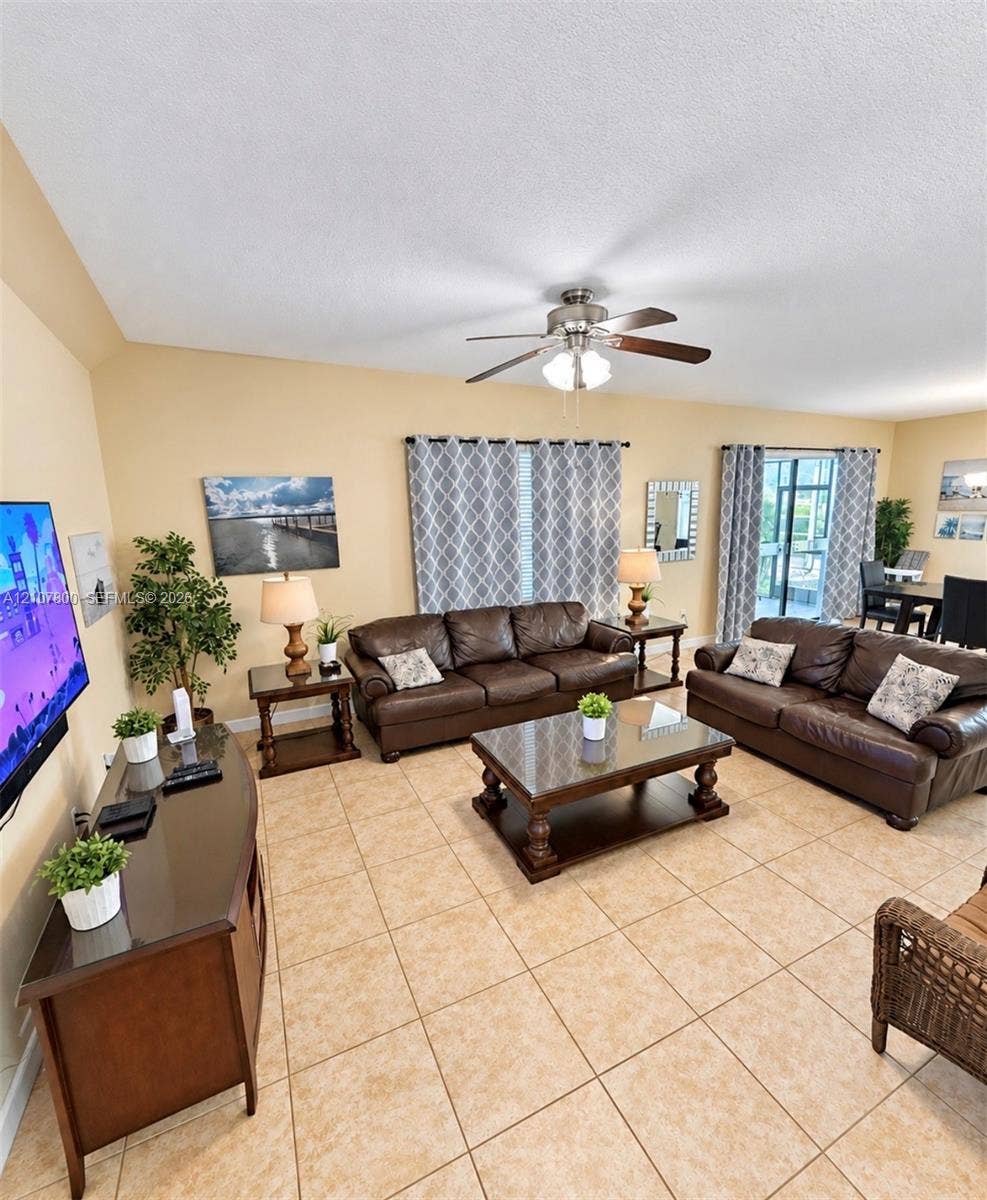 1476 Moon Valley, Davenport, FL 33896 Spacious room featuring vaulted ceilings, neutral wall tones, large-format tile flooring, a central ceiling fan with integrated lighting, and glass sliding doors