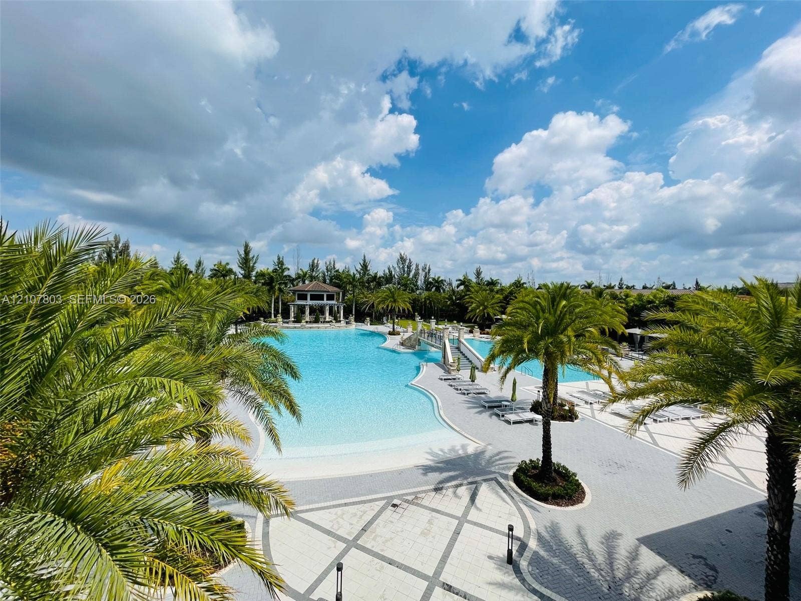 8620 NW 97th Avenue, #205, Doral, FL 33178 Extensive swimming pool featuring a sloped entry, stone-paver decking, arched stone footbridge, and mature palm trees