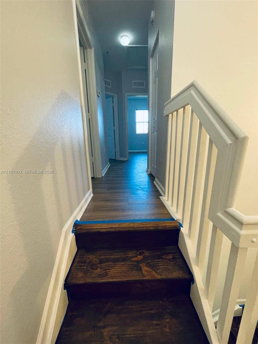 8620 NW 97th Avenue, #205, Doral, FL 33178 Staircase with wood-finish treads and white balustrade, featuring wood-finish flooring and multiple interior doors