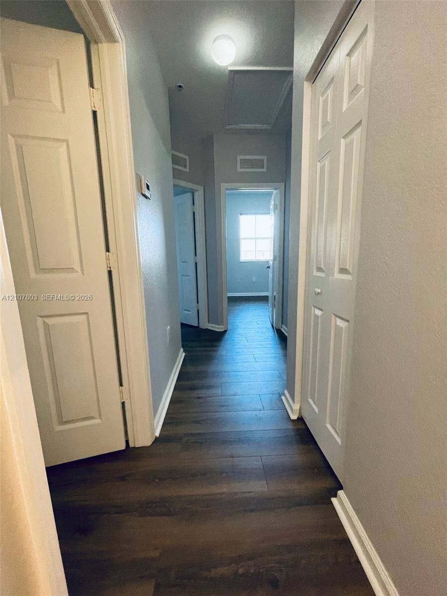8620 NW 97th Avenue, #205, Doral, FL 33178 Interior hallway featuring dark-tone wood-finish flooring, paneled interior doors, and overhead flush-mount lighting