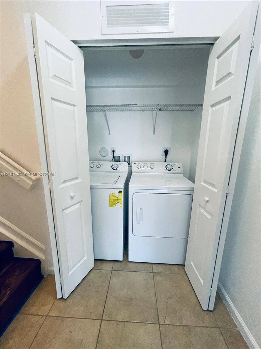 8620 NW 97th Avenue, #205, Doral, FL 33178 Laundry closet featuring double bi-fold doors, white top-loading washer and dryer, and a wire shelving unit