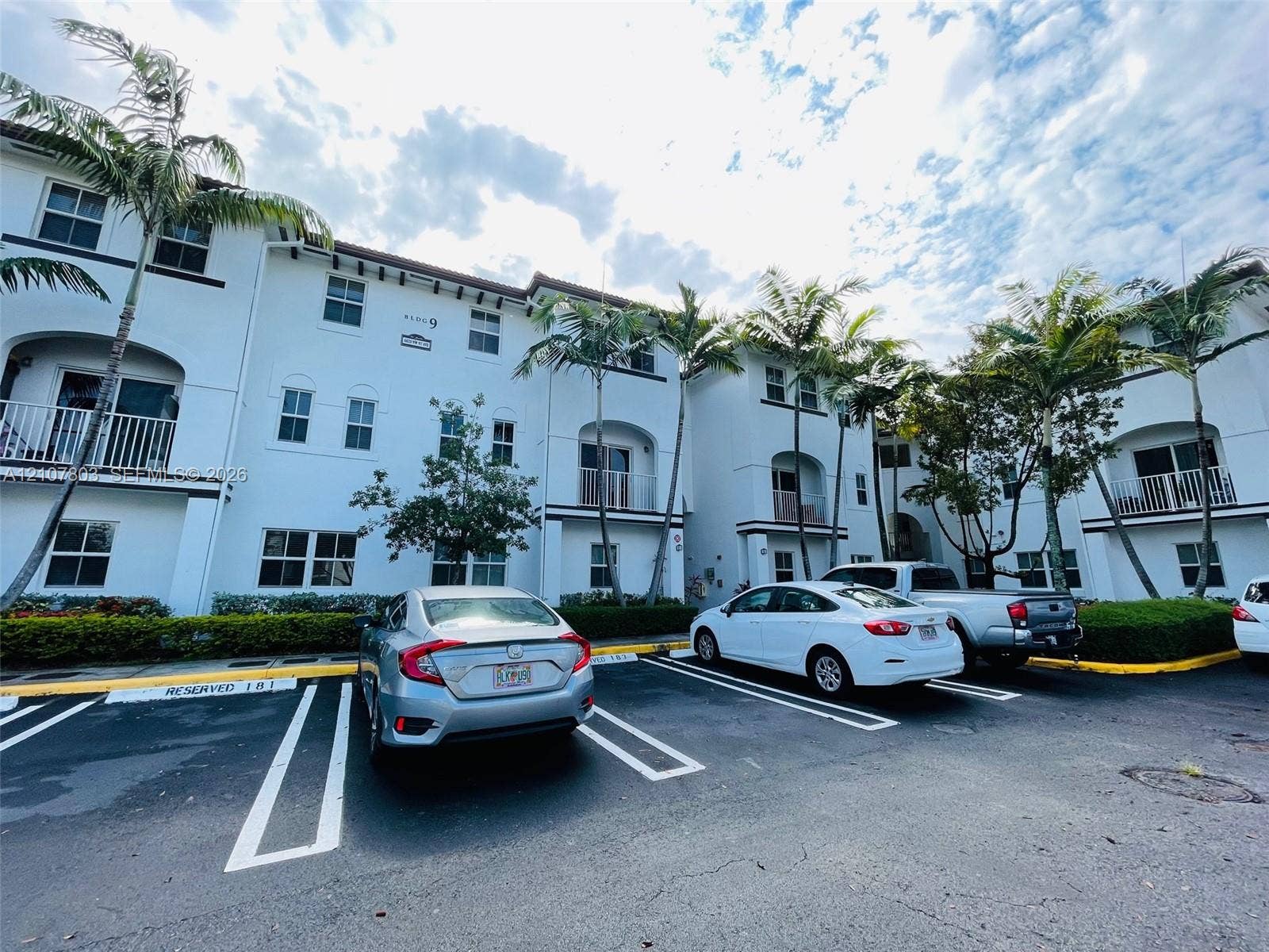8620 NW 97th Avenue, #205, Doral, FL 33178 Multi-story stucco exterior featuring arched balconies, rectangular windows, and mature palm trees