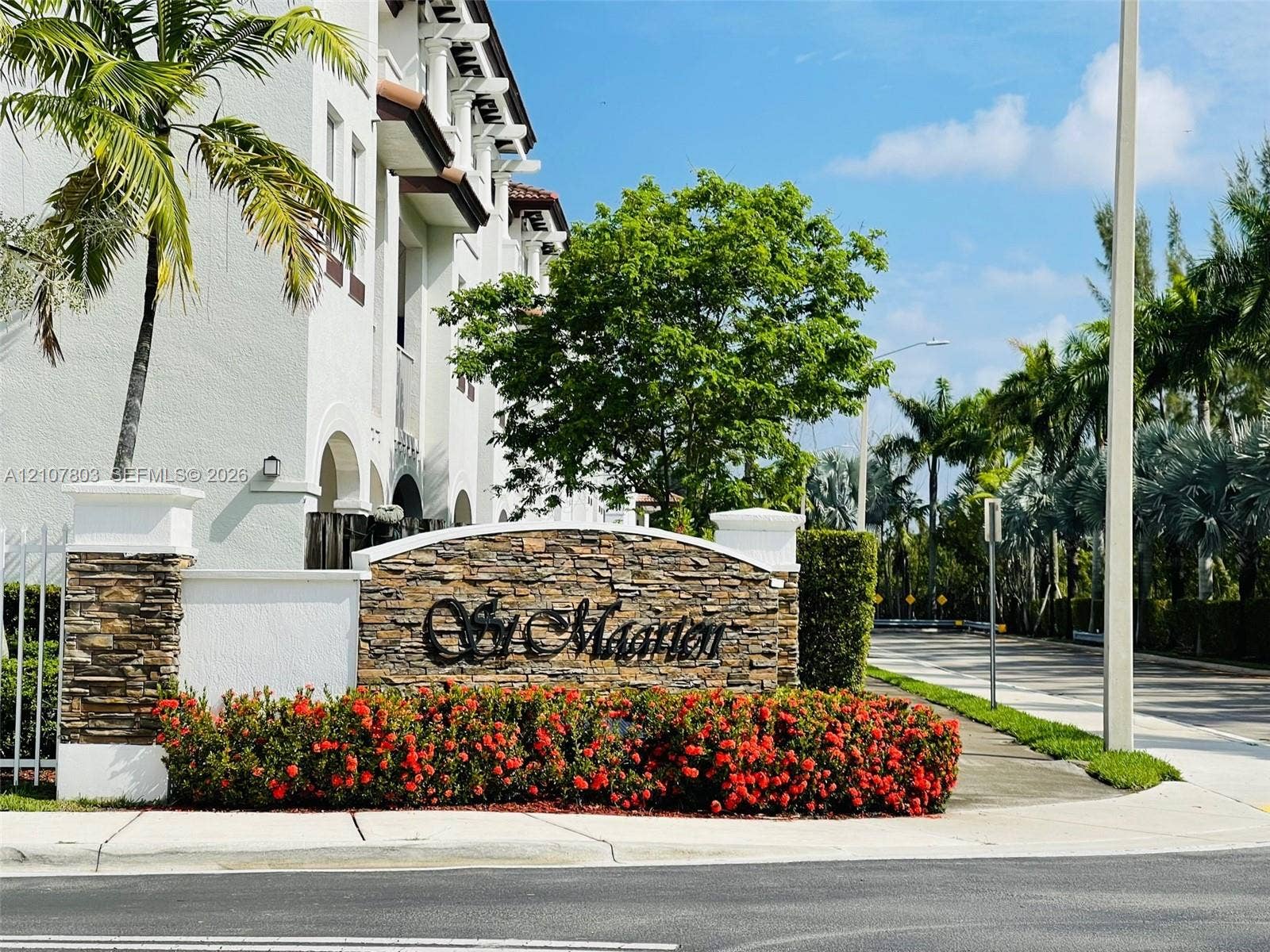 8620 NW 97th Avenue, #205, Doral, FL 33178 Community monument sign featuring stacked stone masonry, decorative metal lettering, and established landscaping with flowering shrubs