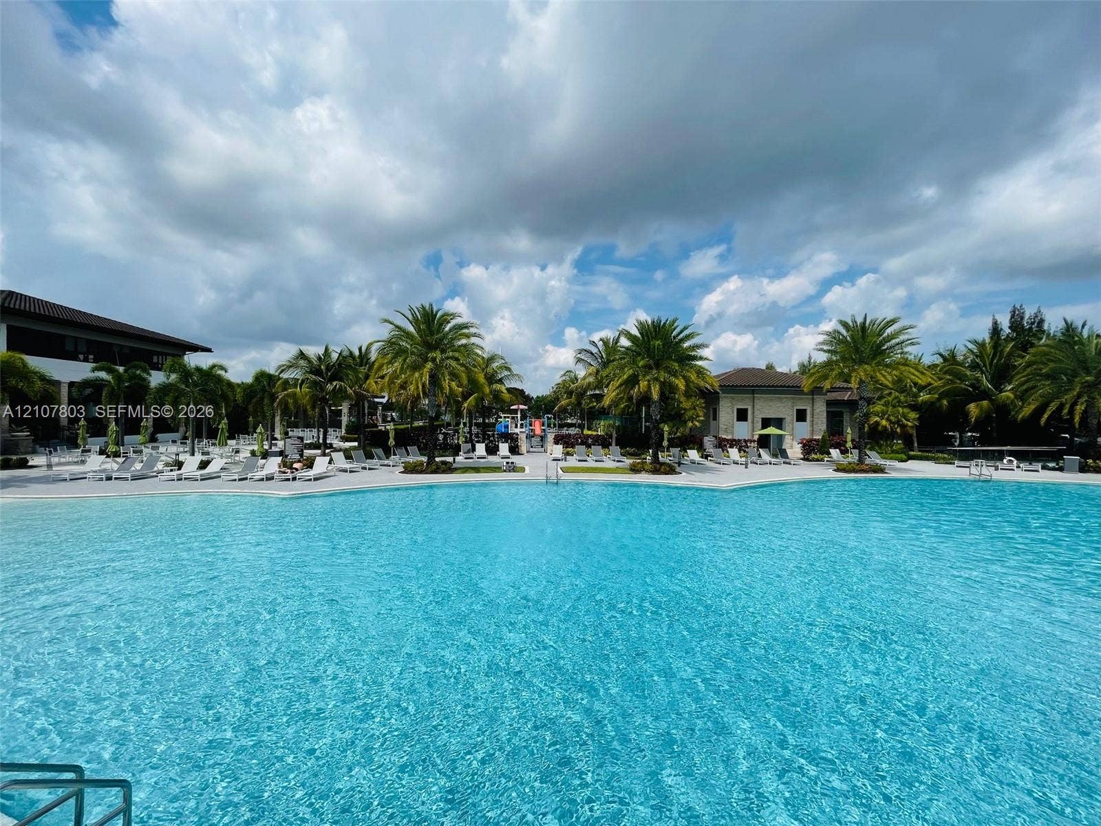 8620 NW 97th Avenue, #205, Doral, FL 33178 Large swimming pool featuring a zero-entry edge, expansive paved surround, and perimeter palm trees
