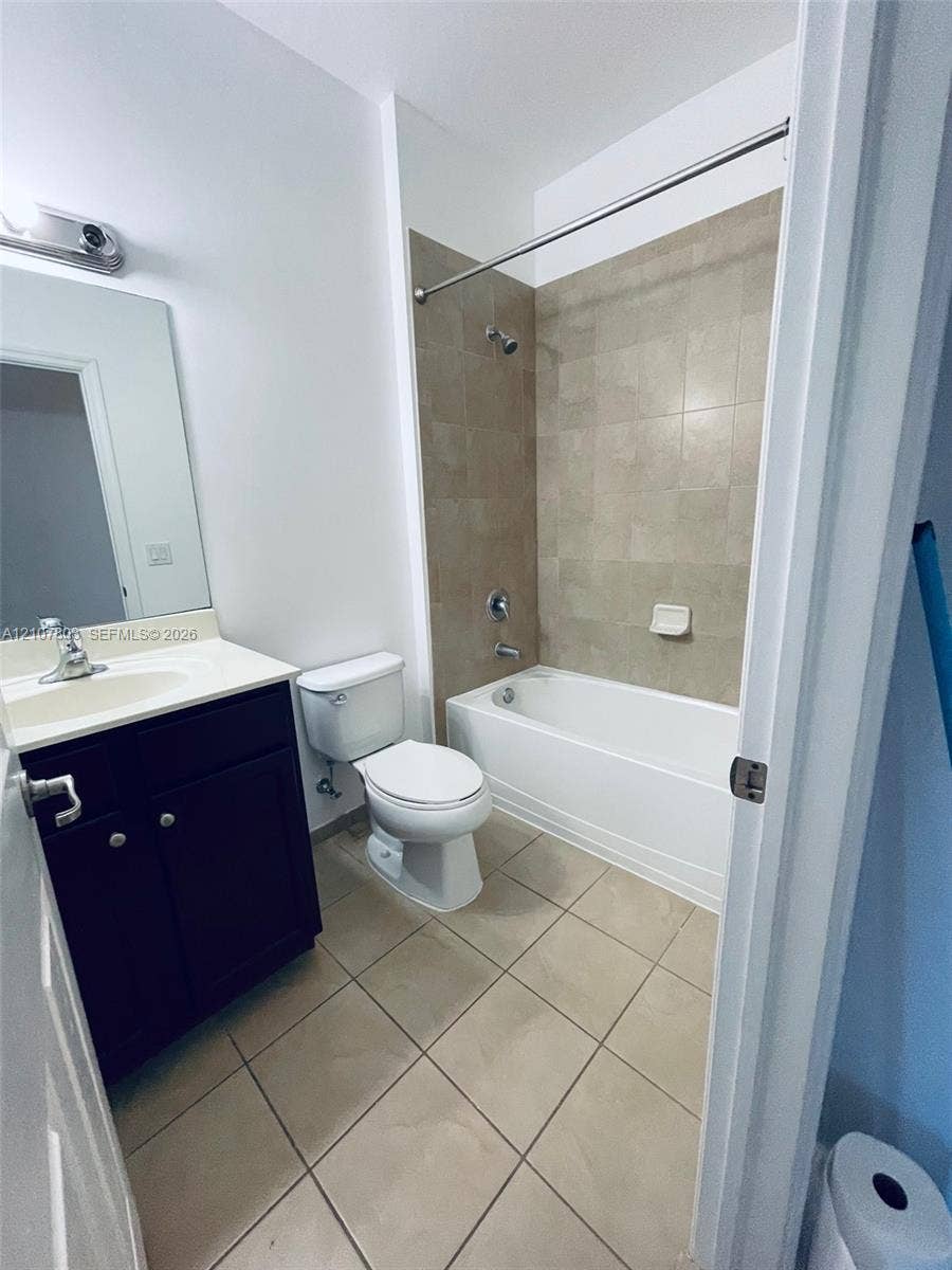 8620 NW 97th Avenue, #205, Doral, FL 33178 Bathroom featuring a dark-finish vanity with a light-toned countertop, square-tile flooring, and a bathtub surround with neutral-tone tiling