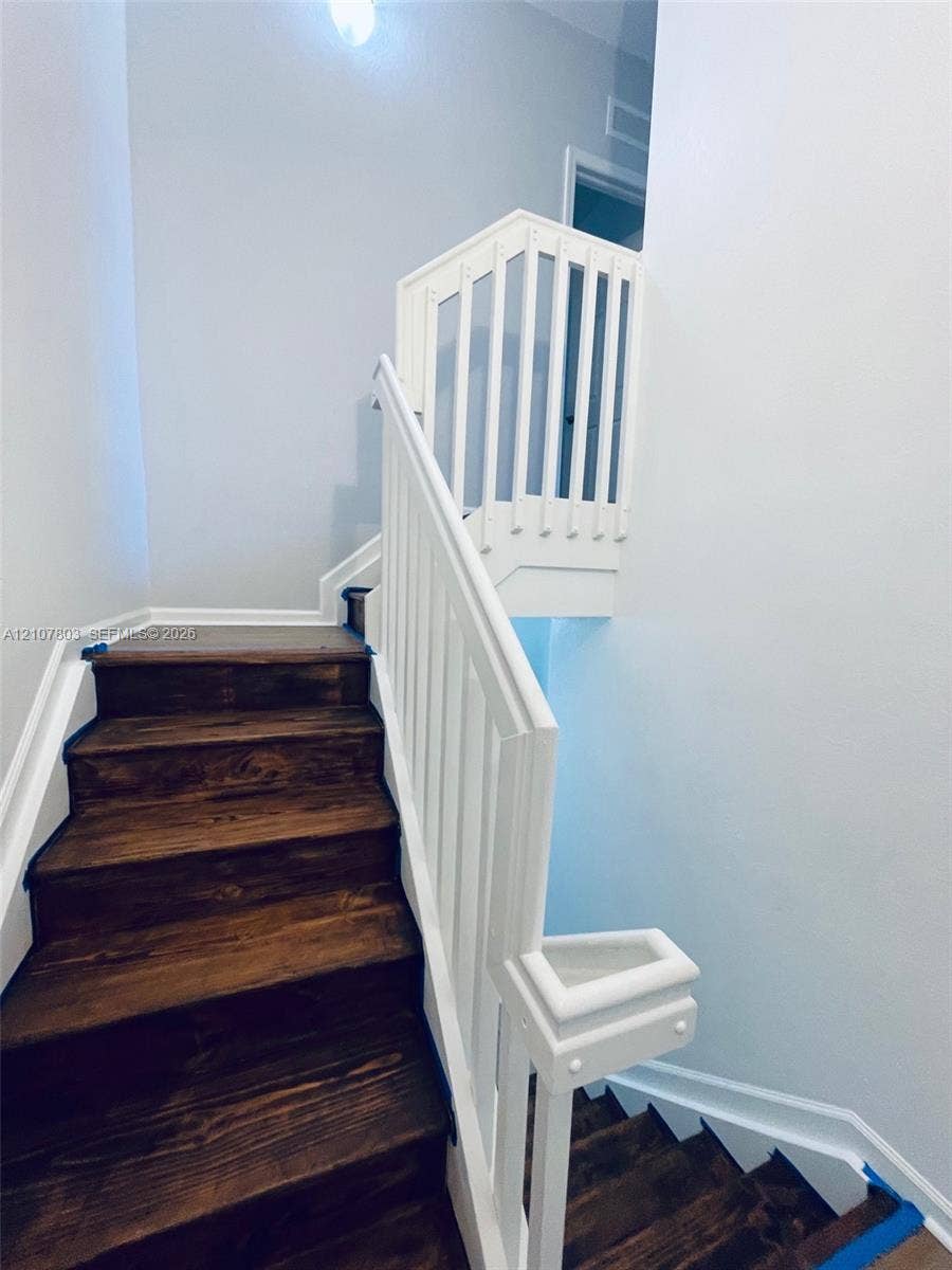 8620 NW 97th Avenue, #205, Doral, FL 33178 Staircase featuring dark-stained wood treads and white-painted handrails with vertical balusters