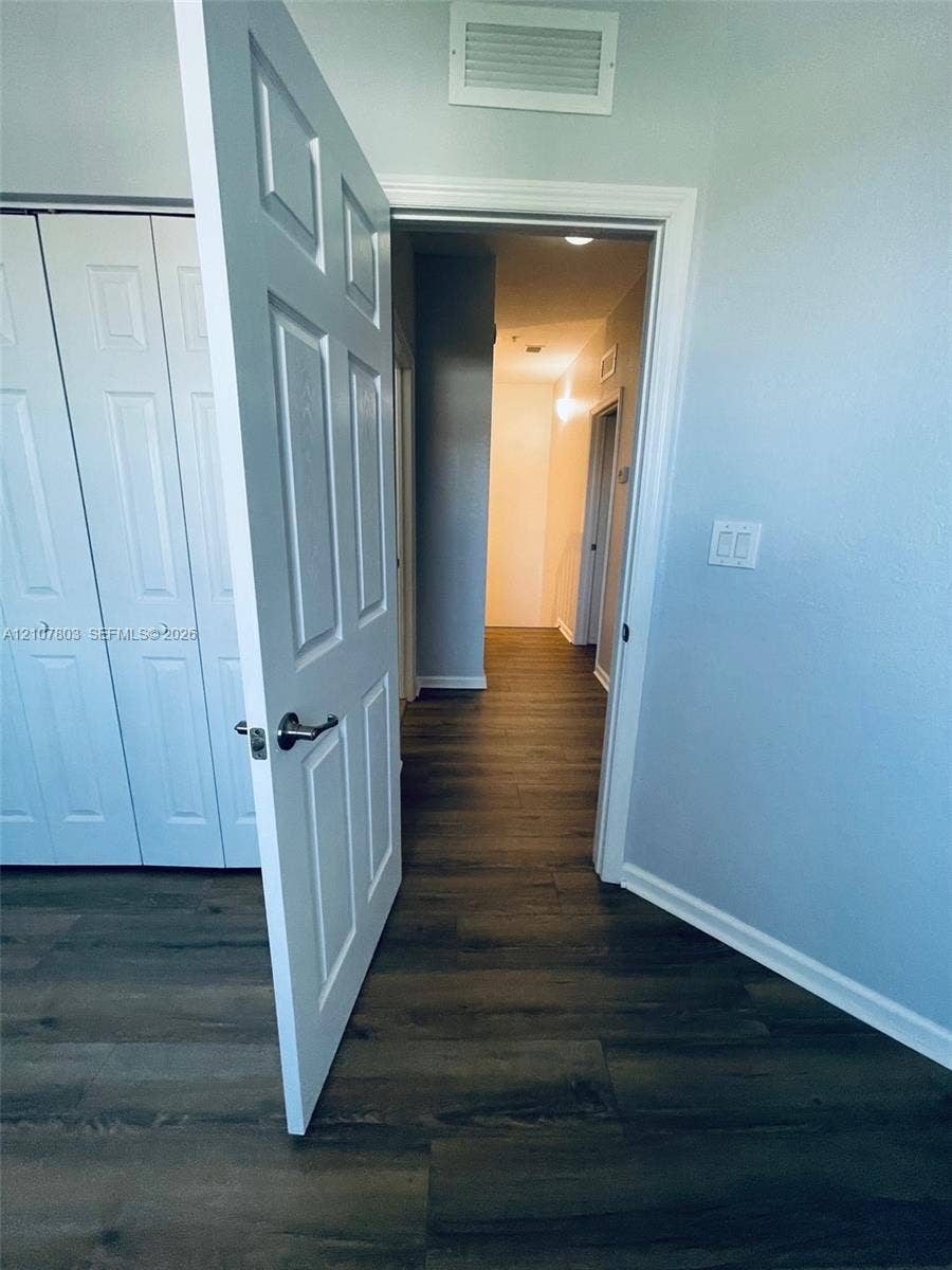 8620 NW 97th Avenue, #205, Doral, FL 33178 Wood-finish flooring, multi-panel interior door with satin nickel hardware, and bi-fold closet doors