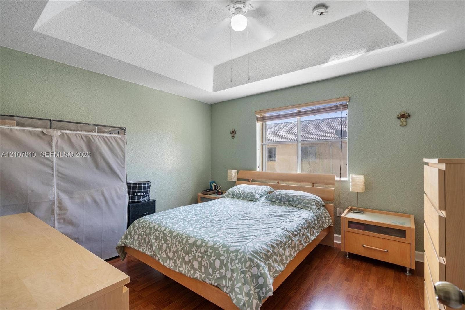 6940 NW 177th Street, #P105, Hialeah, Hialeah, FL 33015 Tray ceiling with centered ceiling fan, wood-finish flooring, and horizontal window with built-in blind