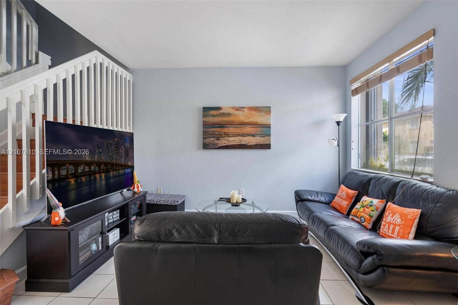 6940 NW 177th Street, #P105, Hialeah, Hialeah, FL 33015 Living area featuring ceramic tile flooring, a large window with blind, and a white staircase with wooden handrail